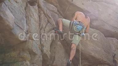 年轻强壮的人攀岩者爬上花岗岩悬崖，伸手抓住。